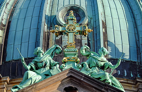 green man, woman, and cross statue during day