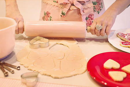 person holding rolling pins with dough