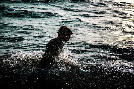silhouette of person swims in body of water during daytime