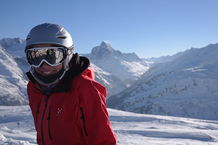 man wearing jacket standing on snowfield wearing helmet and goggles