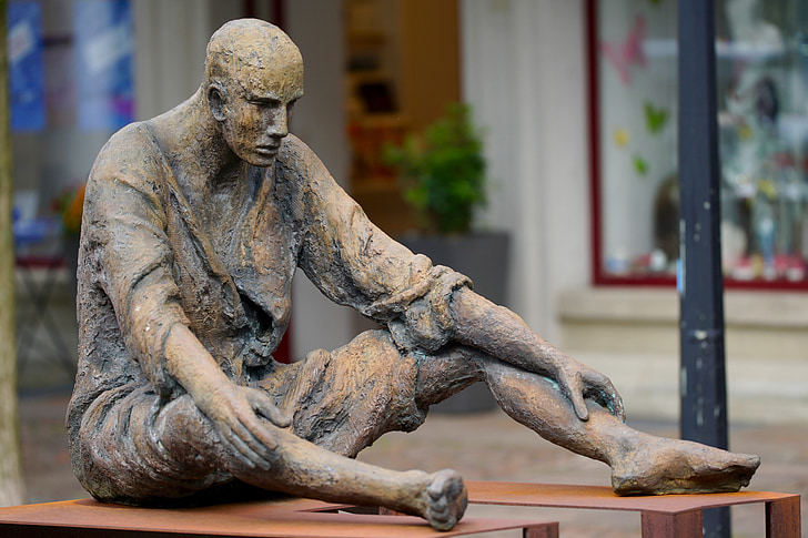man sitting on brown bench statuette
