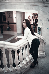 woman wearing white long-sleeved shirt standing on staircas