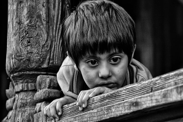 boy holding on brown wooden plank in black in white photography