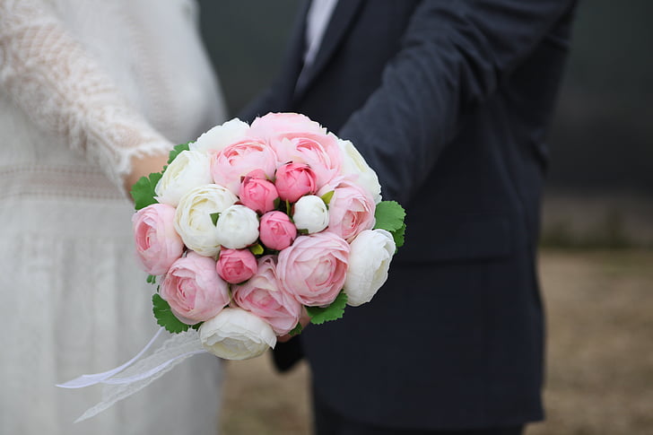 bride and groom holding pink and white flower bouquet