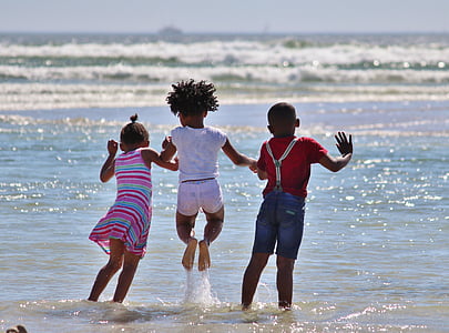 three kids playing on shore during daytime
