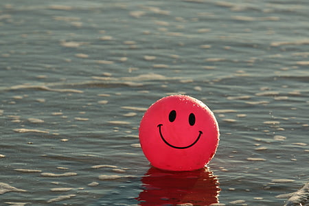 red emoji balloon in sea at daytime