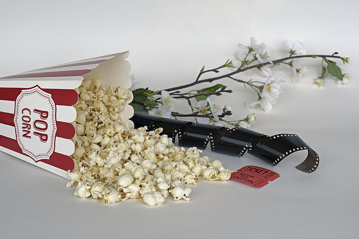 spilled popcorn beside photo negative film and white petaled flower