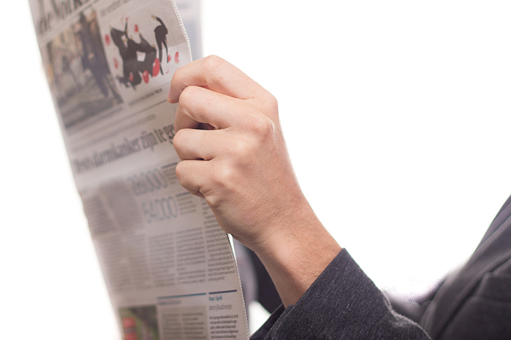 person holding white newspaper