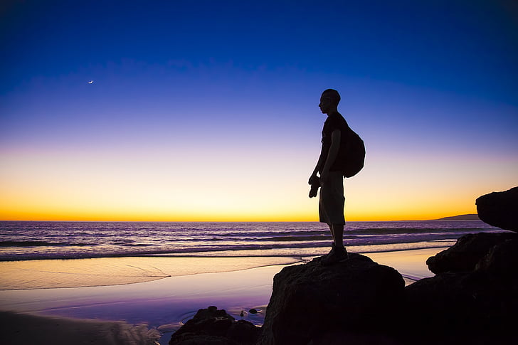 silhouette of man standing near shore