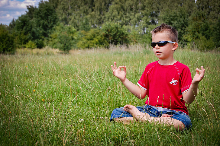 boy in red top sitting on grass