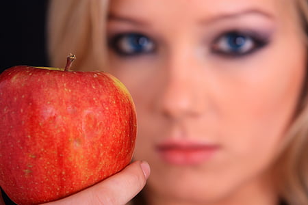 selective focus shot of apple near woman's face