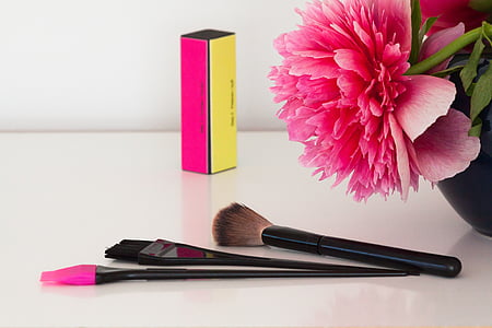 three black handled makeup brushes beside pink flower