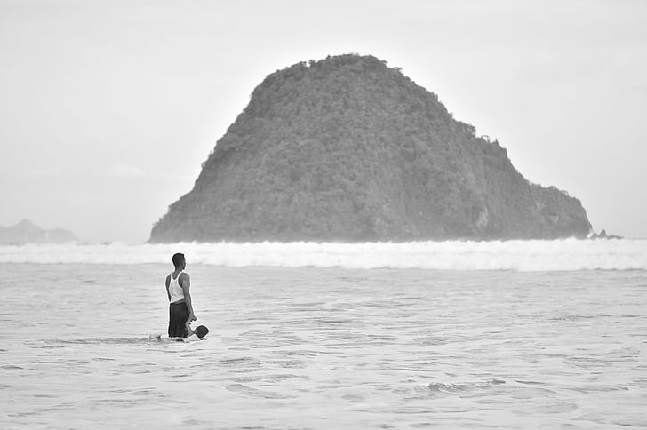 man standing on seashore near island