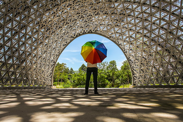 person holding rainbow-colored umbrella