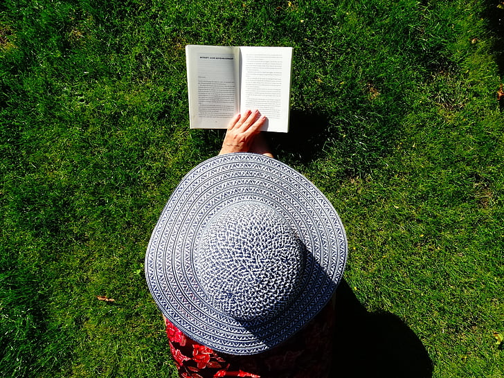 person wearing gray sun hat holding book