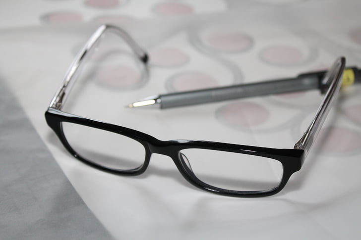 black framed eyeglasses near gray pen on white printer paper