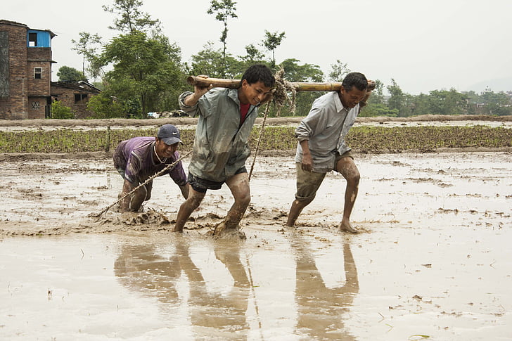 three men standing on mud during daytime