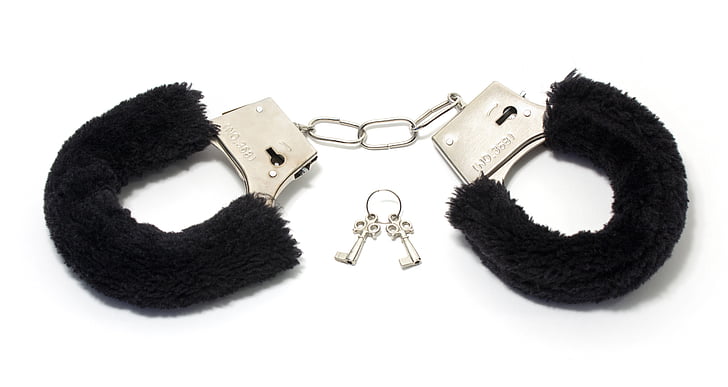 closeup photo of black and silver handcuffs with keys