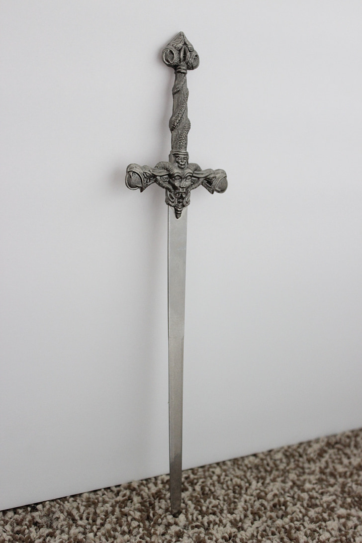 grey stainless steel sword near white concrete wall