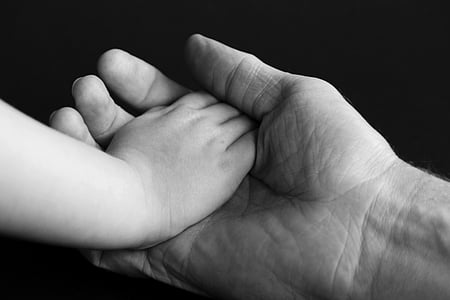 grayscale photo of hand of baby on adult palm