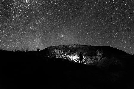 black and white photography of man under starry sky