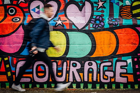 lime lapse photo of man walking near graffiti wall