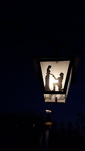 photo of black outdoor lamp with woman and man shade