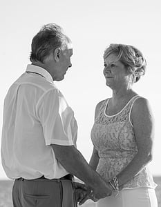 greyscale photography of man and woman facing and holding hands on wide field
