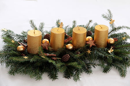 closeup photo of four pillar candles with green leaves