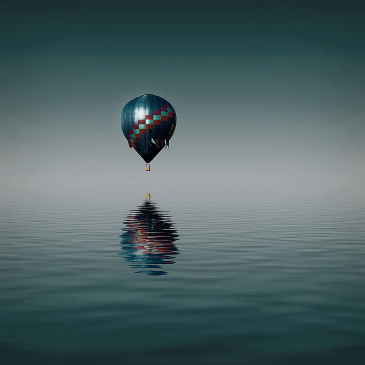 hot air balloon flying over body of water