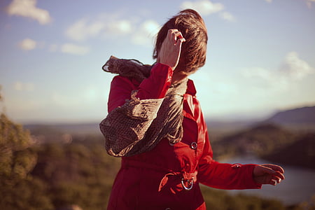 woman wearing red leather coat with brown scarf scratching her head selective focus photography