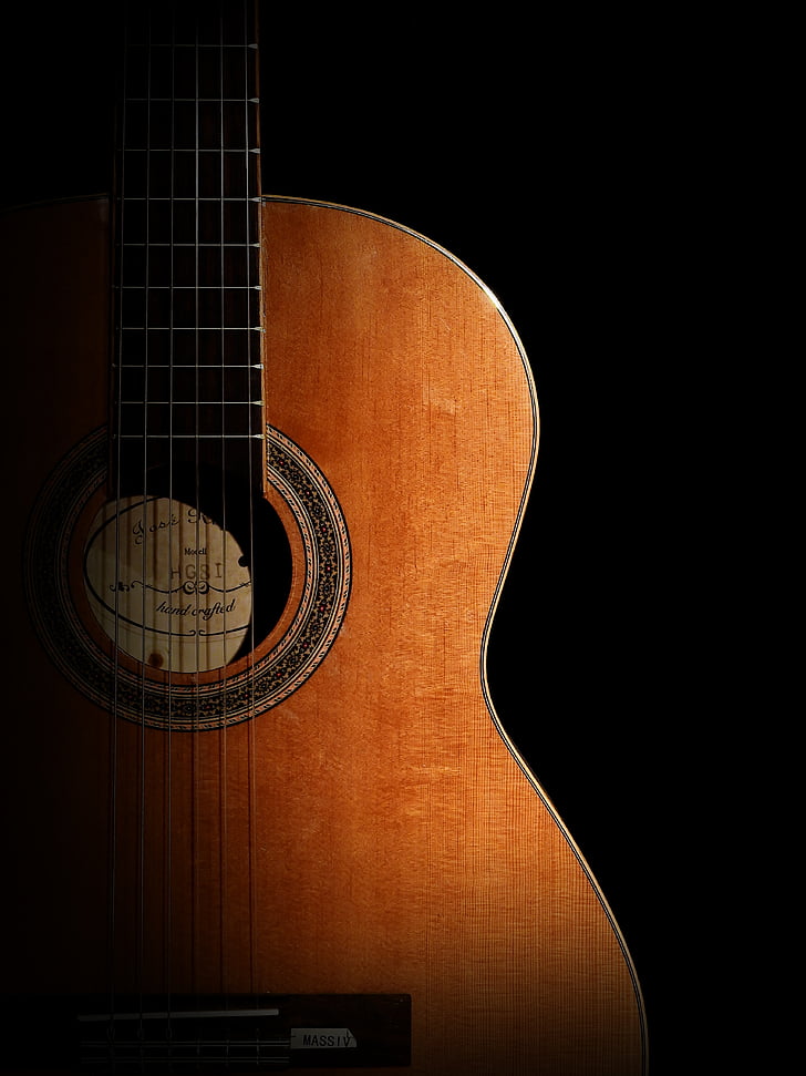 photography of brown classical guitar in dark background