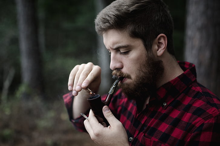 man in black and red gingham dress shirt holding smoking pipe