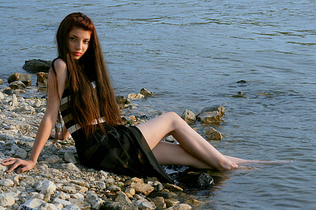 woman wearing black dress sitting on shore