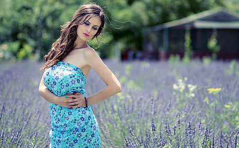 woman standing beside field of lavender flower near house