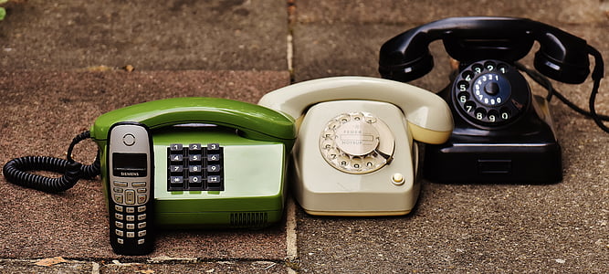 green, white, and black corded telephones