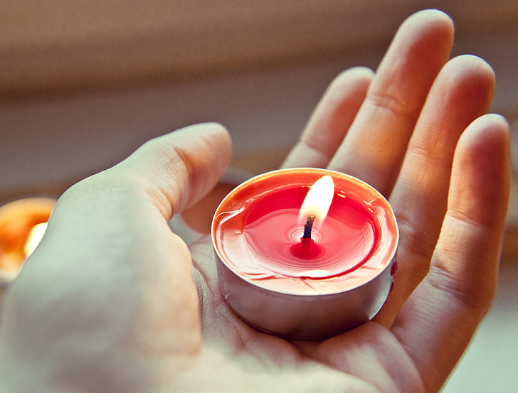 person holding red tealight candle