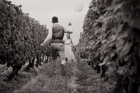 grayscale photography of groom holding balloon while running towards his bride