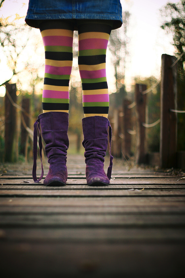 person wearing purple boots an stripe pants standing on dock