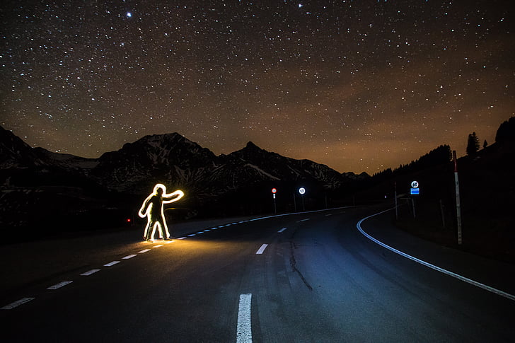 man crossing road time lapse photography