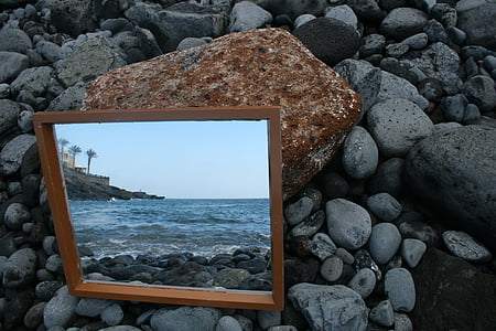 square brown wooden framed mirror on grey pebbles