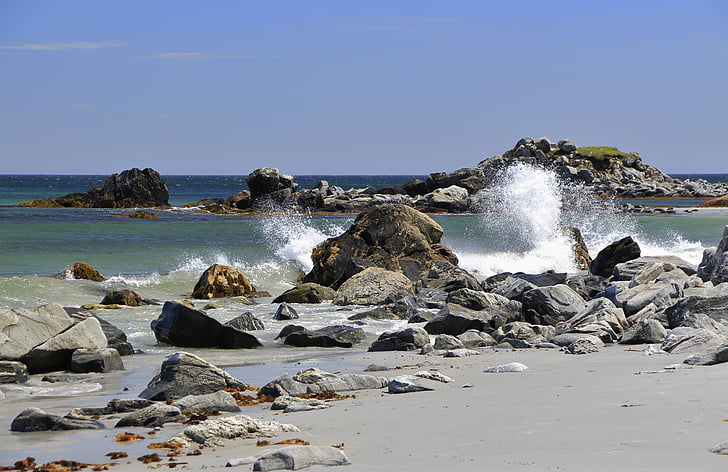 sea waves crashing on rocks under blue sky