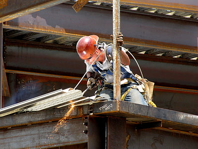 man wearing white shirt and red hard hat holding cutting torch
