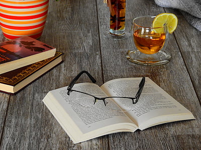 eyeglasses on book beside glass cup