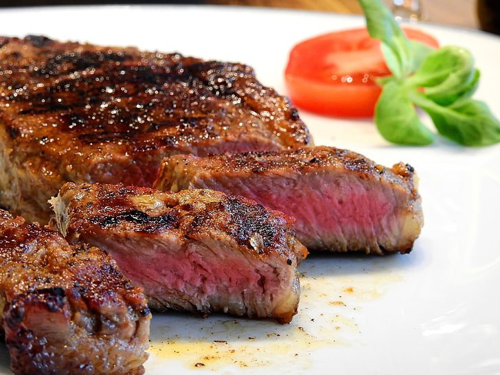 roasted steak with sliced tomato on white plate
