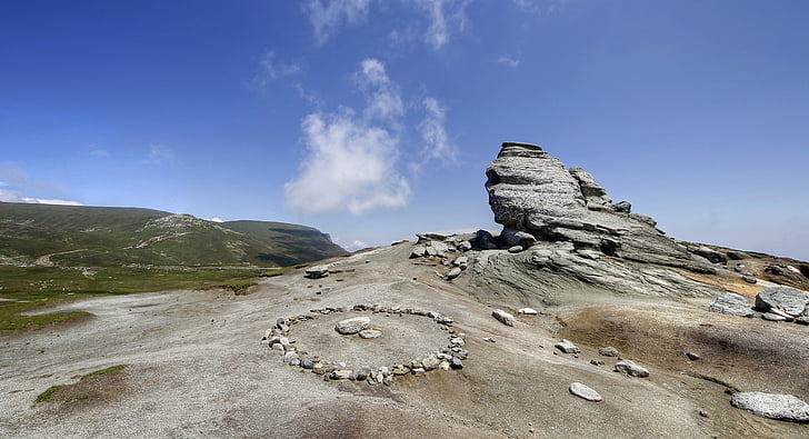 round gray stone formation under white clouds and blue skies at daytime