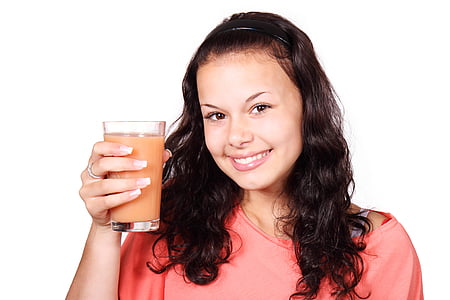 woman holding clear drinking glass with pink liquid