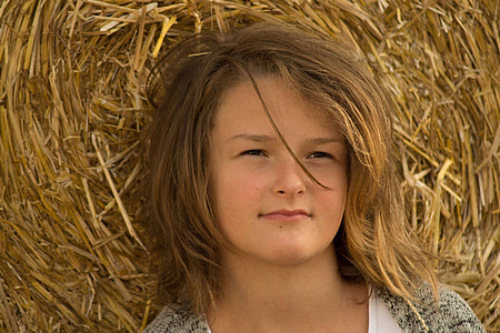 woman in gray top with hay background
