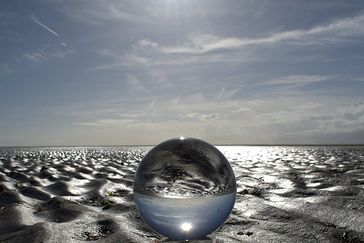 round clear glass ball on sand