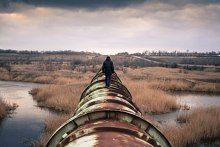 photo of man standing on green steel pipe